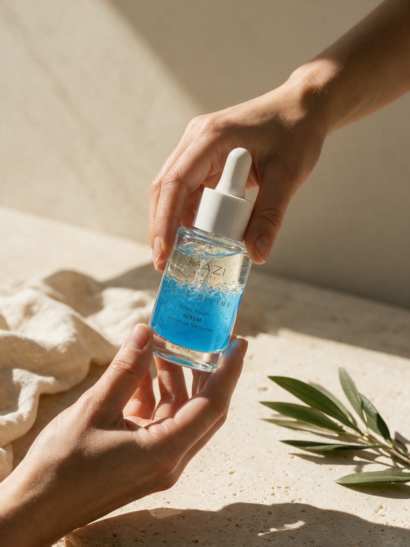 Two hands shake the Aqua Divine serum bottle so the clear and blue phases swirl together