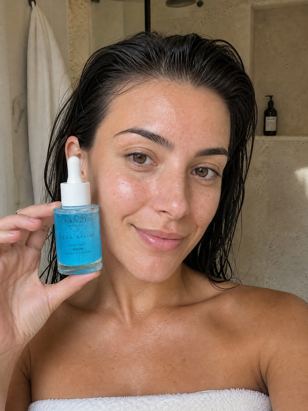 A woman with wet hair holds the Aqua Divine serum bottle beside her face