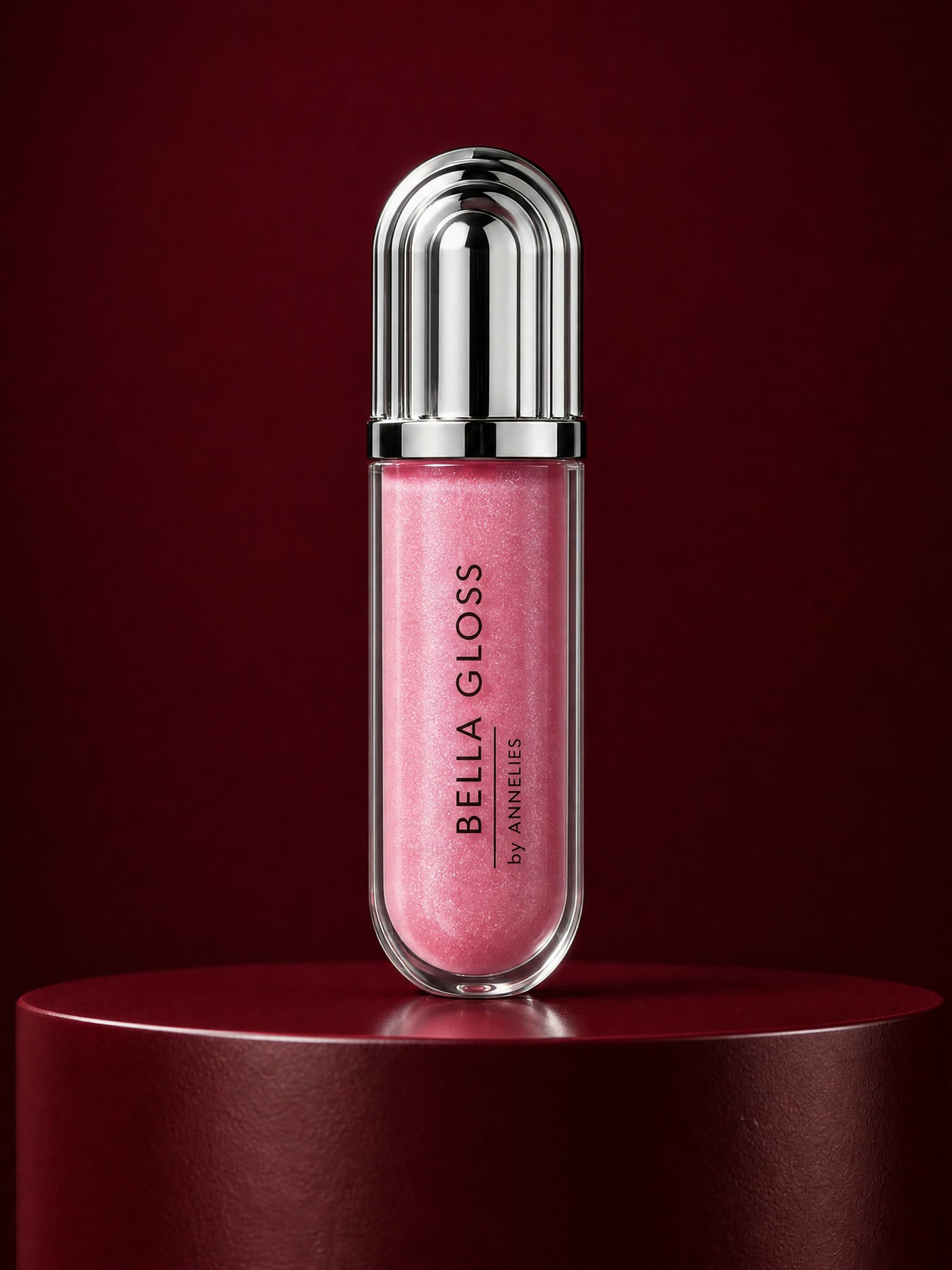 The Bella Gloss tube in rose pink shimmer on a deep bordeaux podium