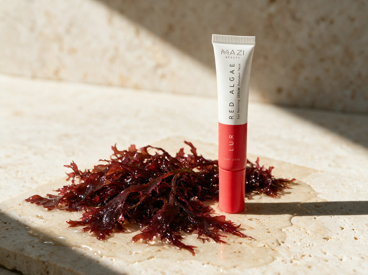 The closed LUR Red Algae tube standing on travertine beside wet fronds of red algae