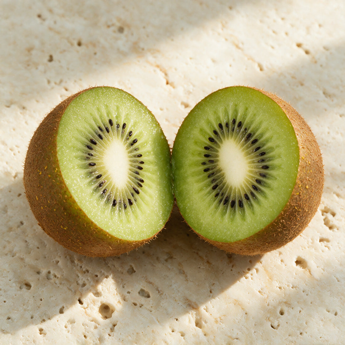 Two kiwi halves on travertine in the sun, the ingredient in the Kiwi Bounce day cream