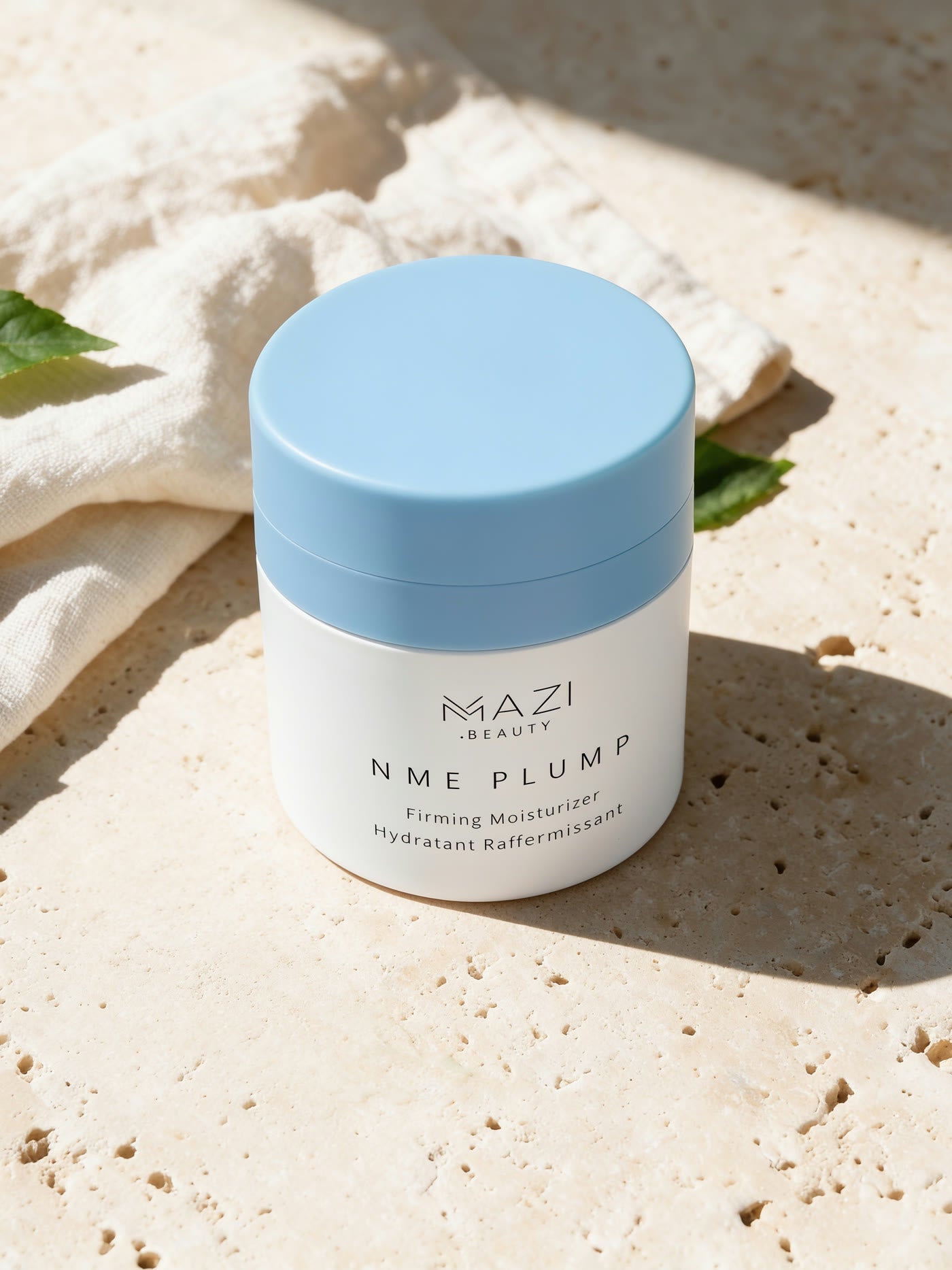 Le pot fermé de crème NME Plump au soleil sur du travertin, à côté d'un lin froissé et d'un brin d'olivier