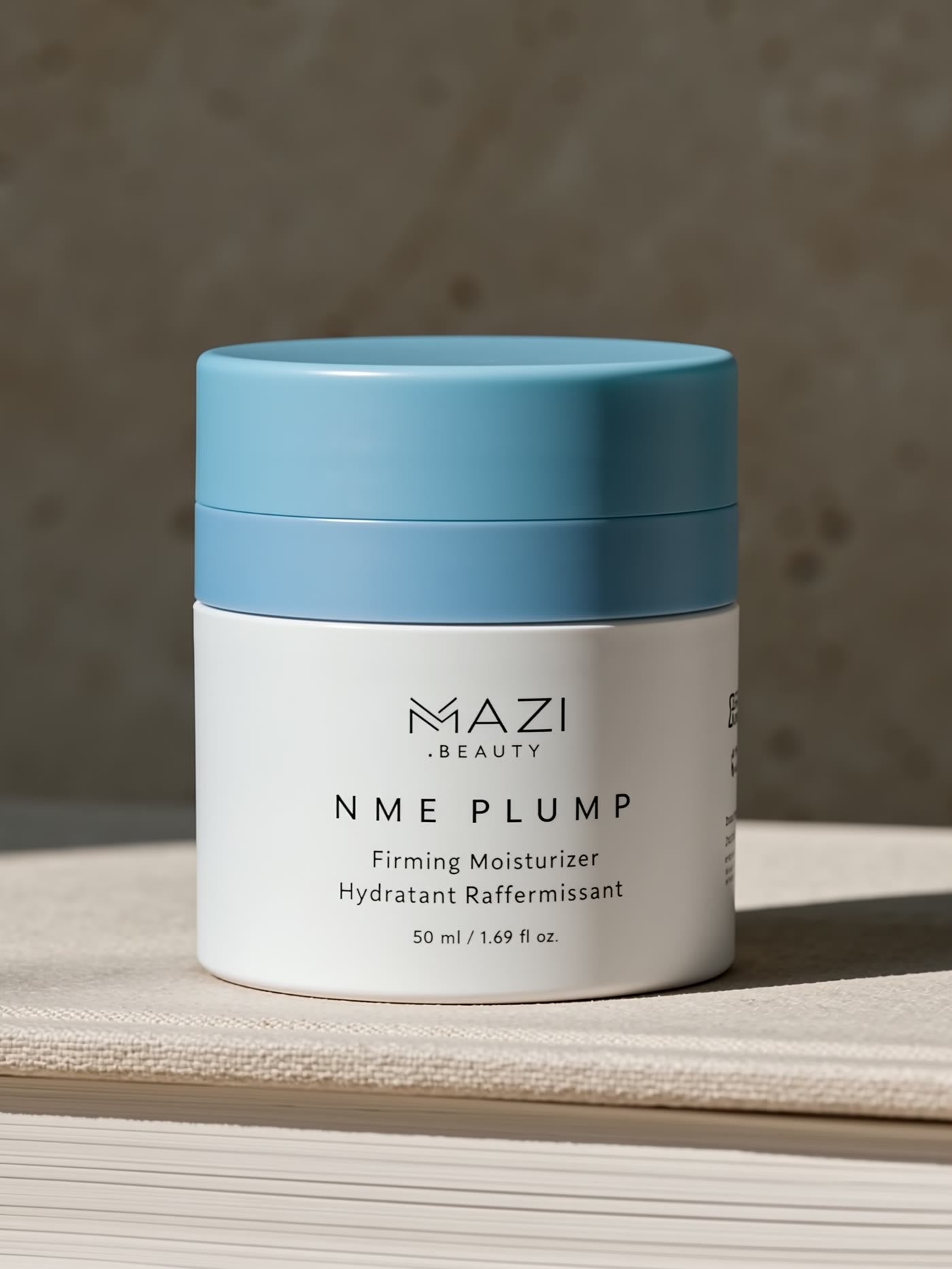 Le pot fermé de crème NME Plump sur une pile de livres contre un mur en travertin
