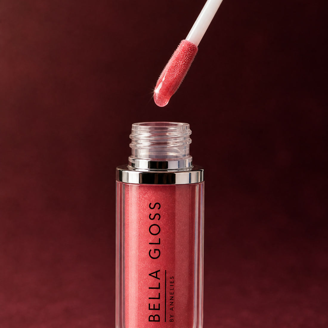 The Bella Gloss lip gloss applicator hovers above the open tube, loaded with gloss