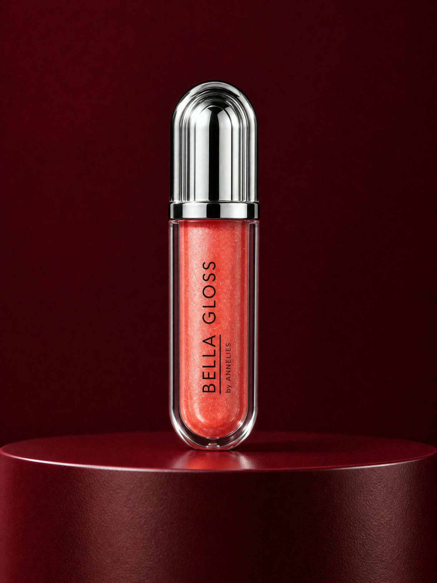 De tube Bella Gloss in lichtroze shimmer op een diepbordeaux sokkel