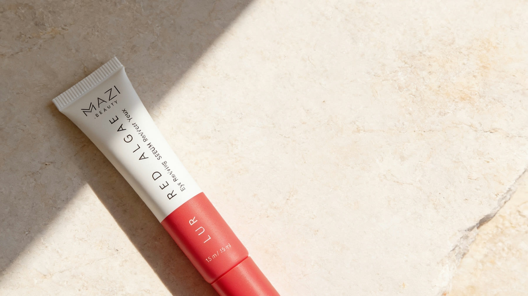 The LUR eye serum tube rests on travertine in raking light
